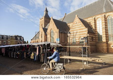 Leerdam, Netherlands, 4 january 2017: market stall with passing bicycle and large church in old town of Leerdam in The Netherlands