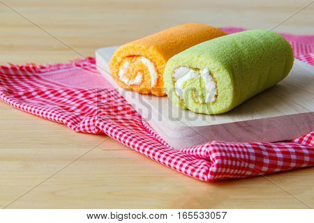 focus Jam roll green and orange on wood plate Put on a red plaid background.