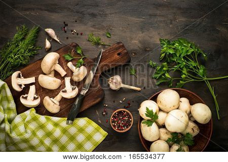 Sliced mushrooms and ingredients for cooking at dark wooden table. Space for text. Ingredients for cooking food background.