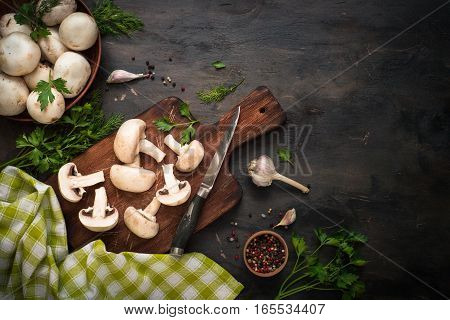 Sliced mushrooms and ingredients for cooking at dark wooden table. Space for text. Ingredients for cooking food background.