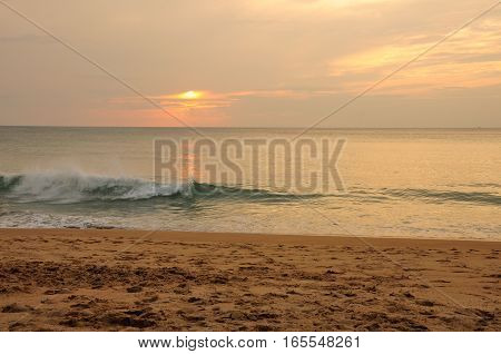 The setting sun reflecting off of the Andaman sea off of Phuket Thailand at Mai Khao beach.