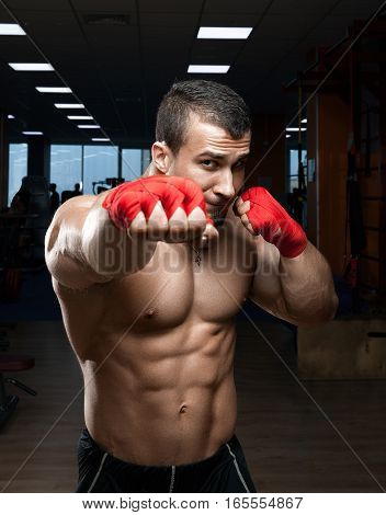 Fighter boxer standing staring strong on black background. Young masculine caucasian male athlete.
