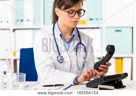 Female Doctor Dialling Number On Telephone