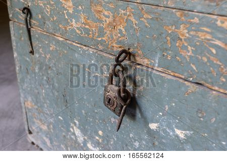 detail of padlock closing an old wooden toolbox, timeworn paint
