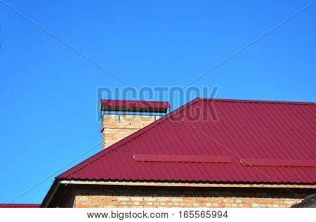 New Metal Red House Roofing Construction. Metal roof tiles installation.
