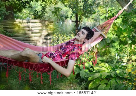 man lying in a hammock in the green garden