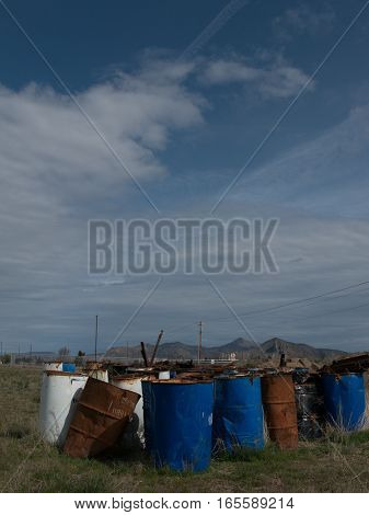 Old rusting empty and discarded oil drums in a field at a rail yard just North of Redmond in Deschutes County in Central Oregon on a sunny spring day.