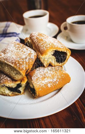 Baked sweet buns with poppy and coffee on wood table