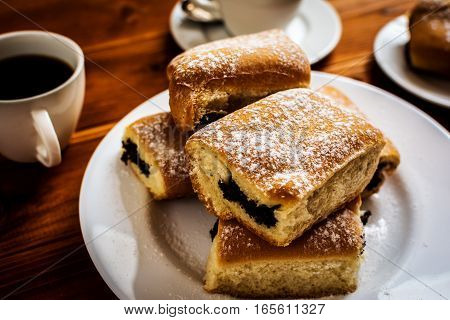 Baked sweet buns with poppy and coffee on wood table
