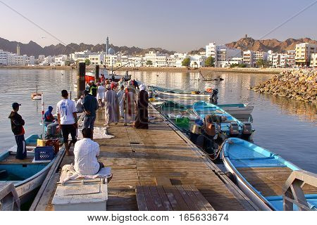 MUSCAT, OMAN - FEBRUARY 11, 2012: Fisherman at The Muttrah Fish docks early morning with Muttrah corniche in the Background