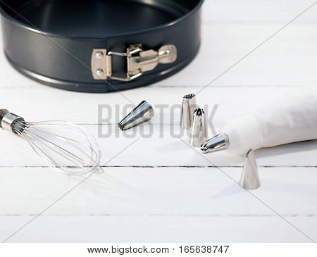 Pastry bag and tips for decorating cakes and cookies on white wooden background