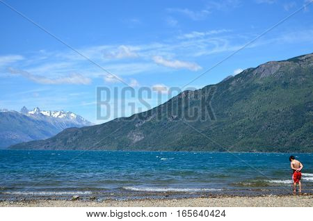 Little boy contemplating the cold lake on a sunny summer day at Patagonia.