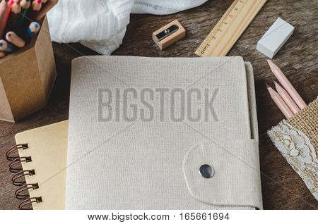 Blank daily notebook with color pencils pencil sharpener ruler and eraser on wooden background