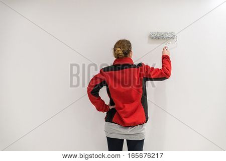 Female Painter With Paint Roller In Front Of Wall As Template