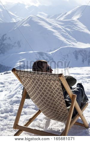 Skier at winter mountains resting on sun-lounger at nice sun day. Caucasus Mountains Georgia region Gudauri.