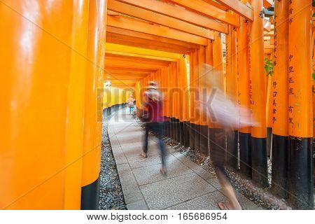 Wide angle view of Torii gates in Fushimi Inari Shrine with blurred tourists in Kyoto, Japan