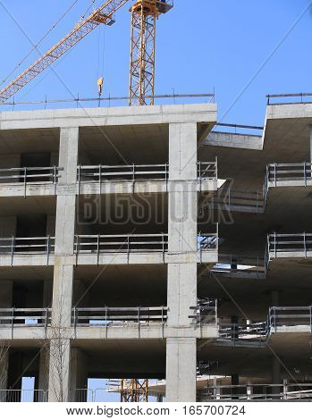 big yellow crane and the huge residential and commercial building under construction made of reinforced concrete
