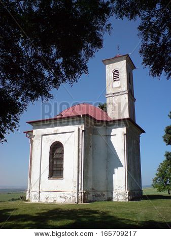 Picture of a small chaple standing on hill covered with trees