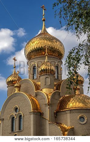 Ukraine Khartsizk . Orthodox Church of the Iberian Icon of the Mother of God . Holy spring . The gilt domes and roof . Bright sunny day blue sky with small clouds.
