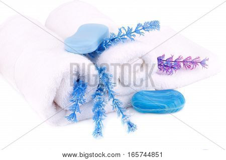 White rolled towels with soaps and flowers on white background.