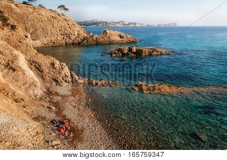 View of the cozy bay of Majorca with azure water hidden wild stone cliff beach and the tourists nudists of Paguera Mallorca Spain