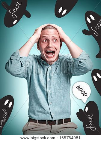 The disappointed young man in blue shirt over blue studio background. Concept of fear and fright