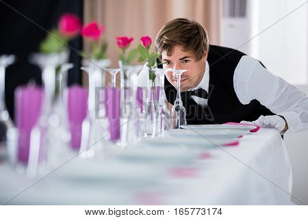 Handsome Waiter Looking At Wedding Table Arrangement At Restaurant