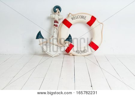 Anchor and life buoy on a white wooden floor.