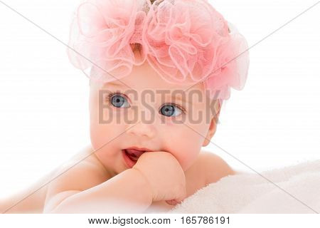 Cute little baby girl with big blue eyes wearing a pink bow.