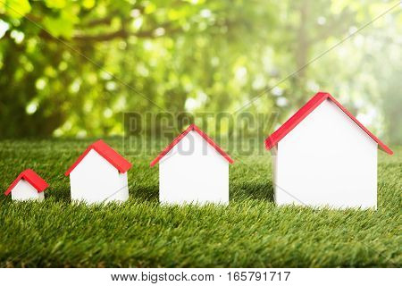 Different Size Of Houses Arranged In Row On Grassy Field