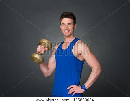 Handsome man with dumbell on grey background, blue t-shirt