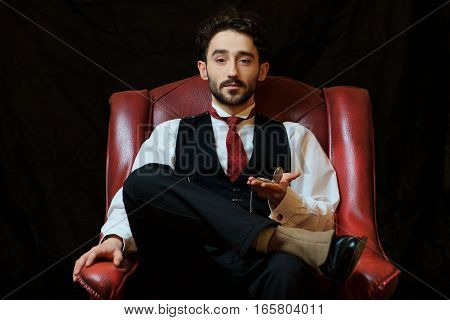 portrait of a young businessman with a pocket watch sitting on a chair.