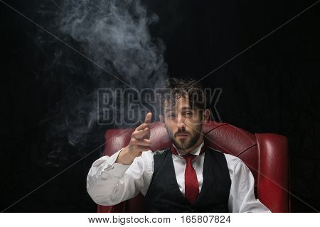 Businessman with smoking gun finger red. red chair on a black background