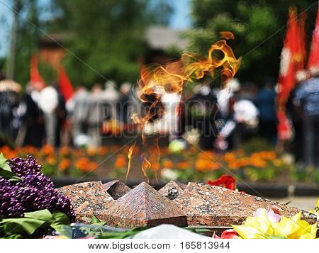 an eternal flame, red banners, veterans, spring flowers, a memorial to the fallen