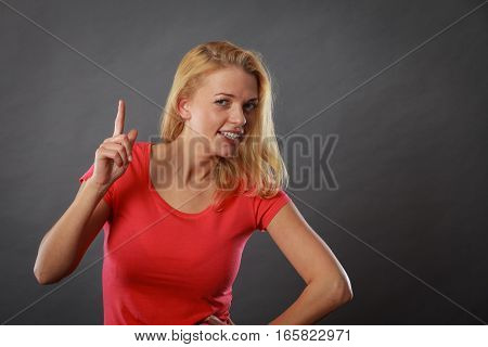 Gestures pointer having idea concept. Happy woman pointing up with one finger. Studio shot on light drk background