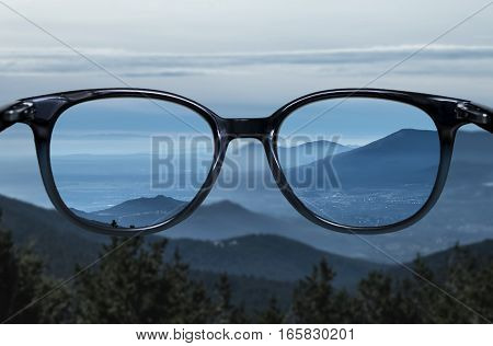 Clear vision through glasses over blue mountain landscape