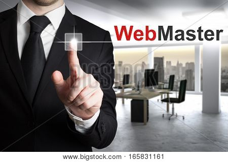 buisnessman in large modern it office pushing button webmaster skyline