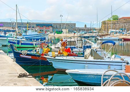 The colorful fishing boats in old port of Ajaccio with the ramparts of the Citadel on the background Corsica France.