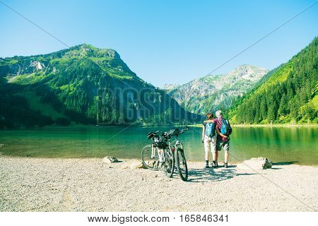 Cycling senior couple taking a break by the lake.