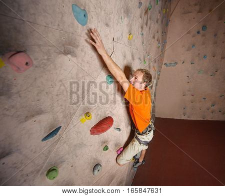 Male Climber Practicing Rock-climbing On A Rock Wall Indoors