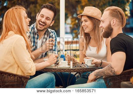 Friends having a great time in cafe.Friends smiling and sitting in a coffee shop drinking coffee and enjoying together.