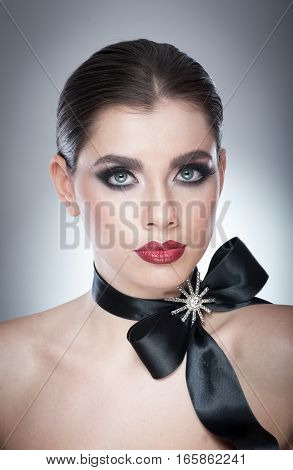 Hairstyle and Make up - beautiful female art portrait with black ribbon. Elegance. Genuine Natural brunette with ribbon - studio shot. Portrait of a attractive woman with beautiful eyes and red lips