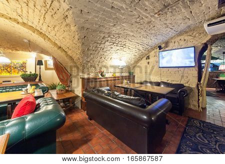 MOSCOW - AUGUST 2014: Interior of a luxury restaurant "PEPPE" in the historic cellar with brick vault. Table with leather sofa in front of the TV