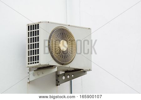 Air conditioner compressor unit on white wall outdoor.