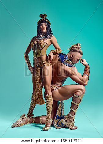 The man and woman in the images of Egyptian Pharaoh and Cleopatra on blue studio background