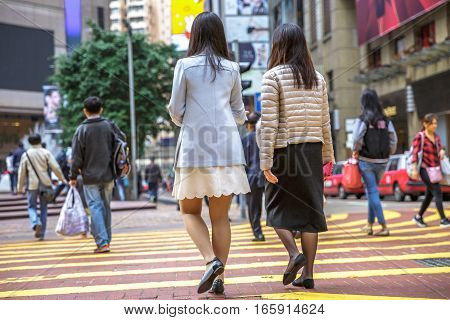 Hong Kong, China - December 6, 2016: Causeway Bay is one of best place for shopping, always full of tourists and business people. Asian couple male collegues crossing the Times Square intersection.