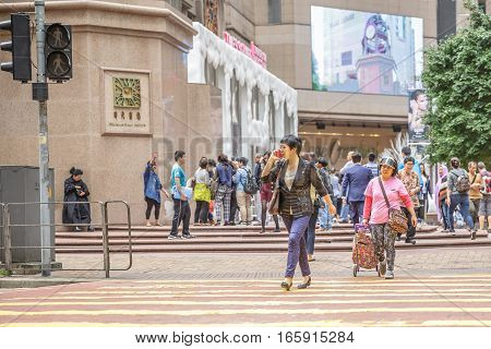 Hong Kong, China - December 6, 2016: Typical busy asian woman with fashion dress talking at her mobile and walking fast in Times Square, Causeway Bay, looking for shopping.