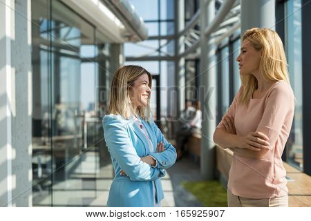 Two female colleagues talking about business in a modern office.