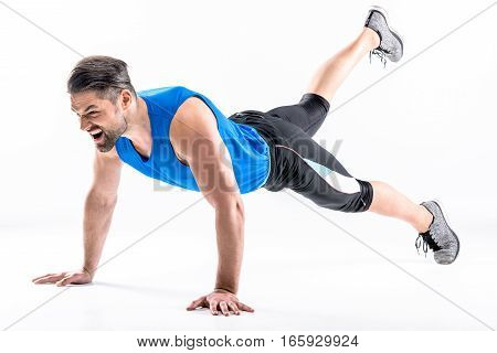 Full length portrait of young athletic man doing plank exercise on white