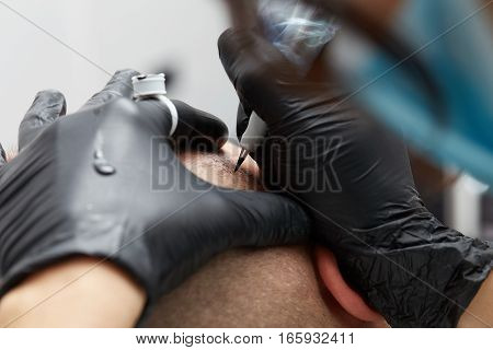 Cosmetologist making permanent makeup on male head - tricopigmentation